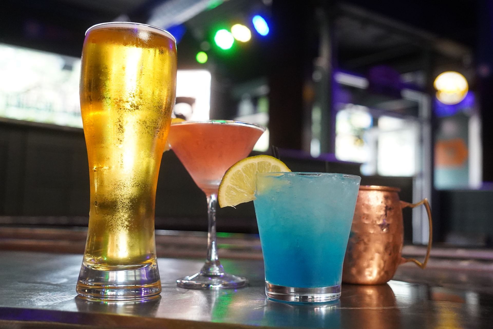 Pilsner, cosmopolitan, blue cocktail and copper mule mug on the bar top