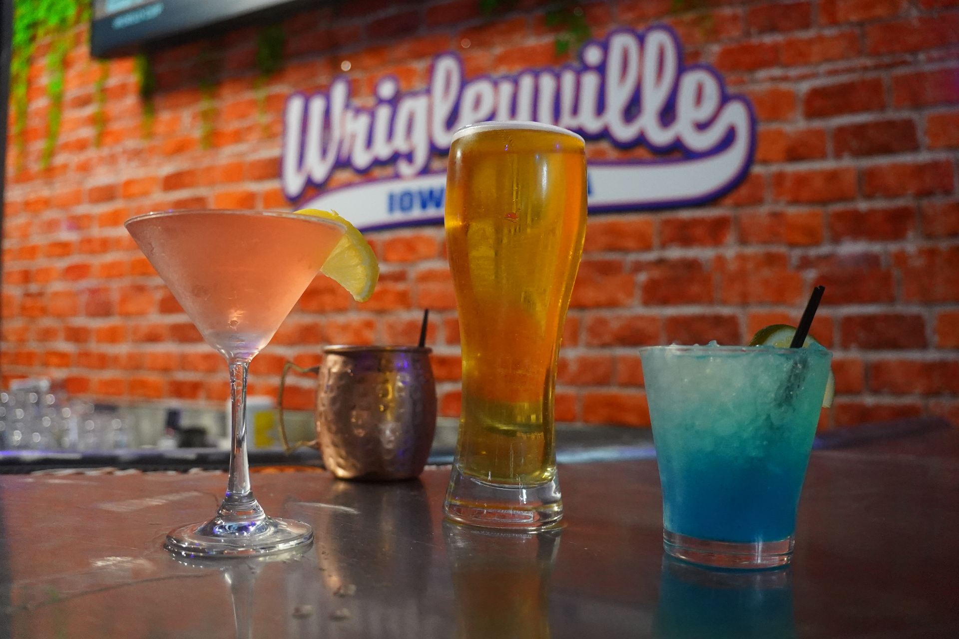 Signature cocktails lined up in front of the Wrigleyville brick wall sign